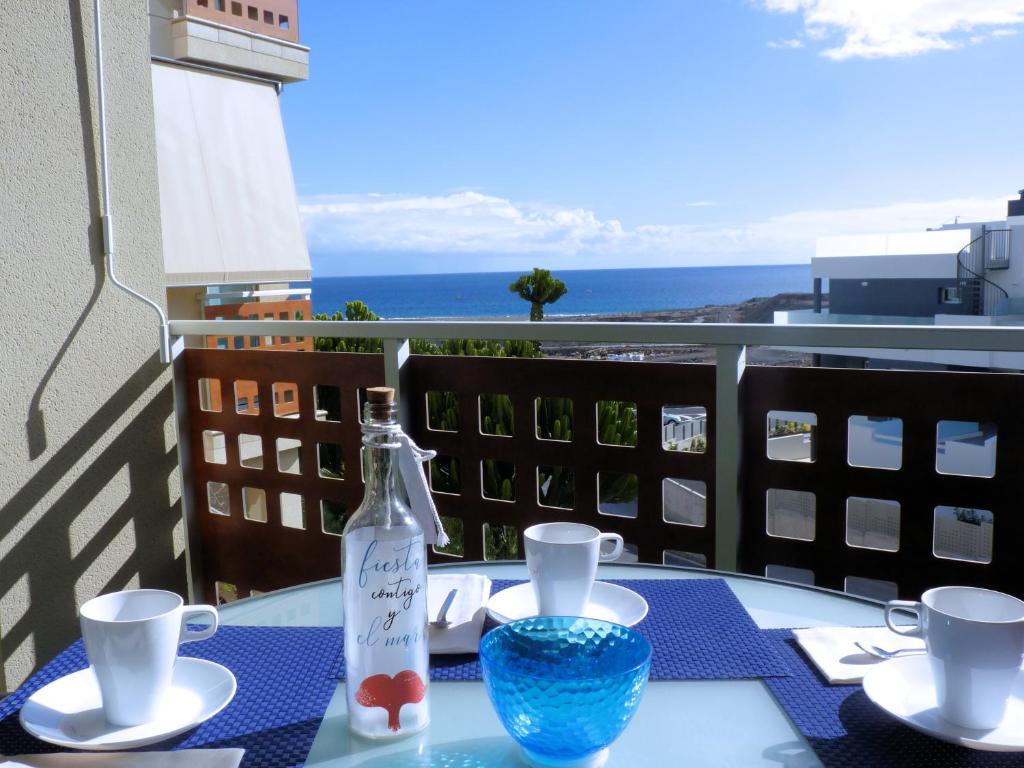 una mesa con una botella y tazas en el balcón en Apartamento VISTA ROJA - LA TEJITA en El Médano