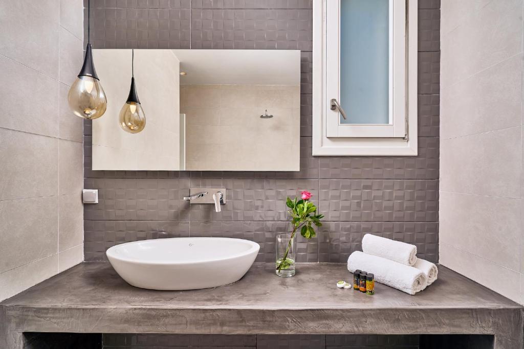 a bathroom with a white sink and a mirror at Arte & Mare Elia Luxury Suites and Villas in Elia Beach