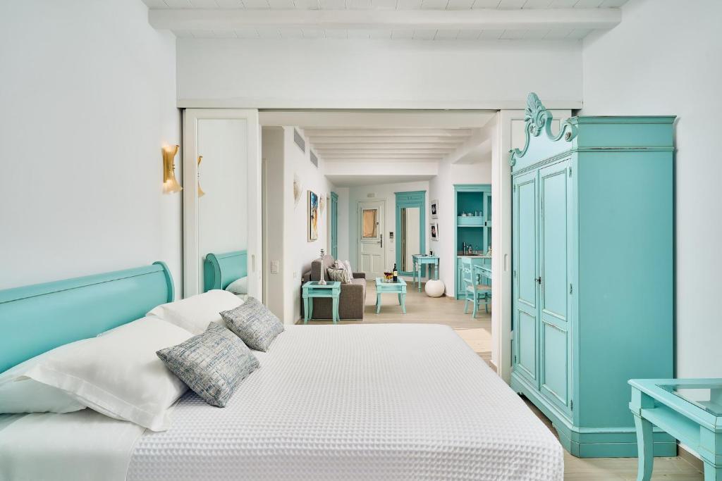 a bedroom with a blue and white bed and a living room at Arte & Mare Elia Luxury Suites and Villas in Elia Beach