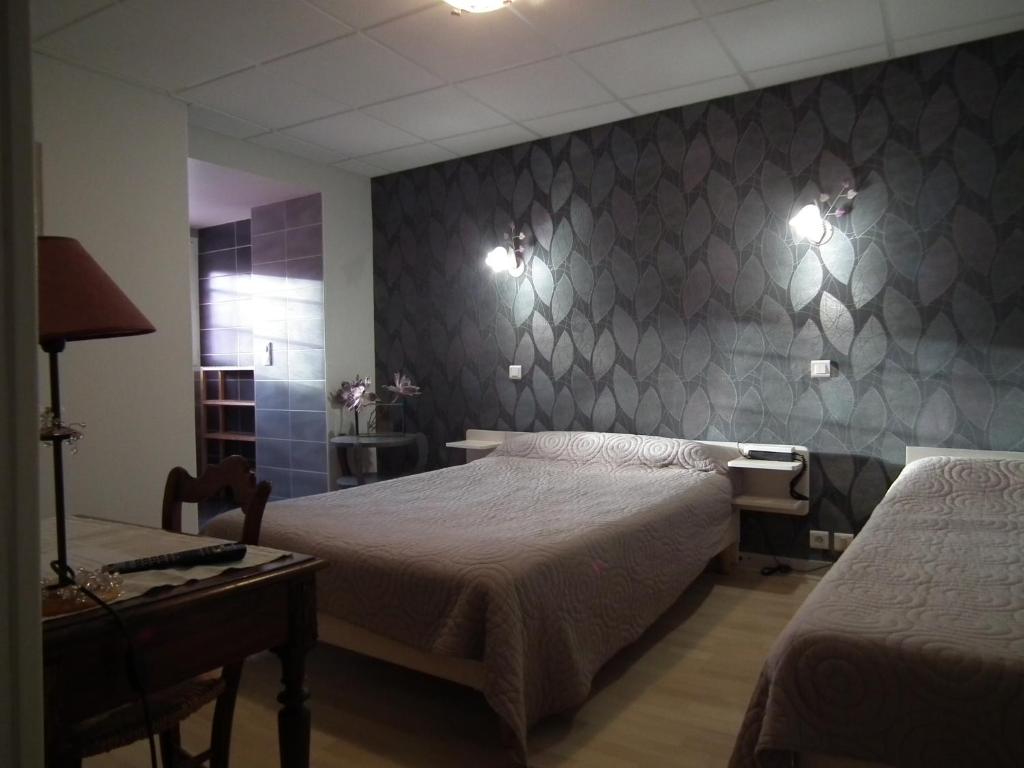 1 dormitorio con 2 camas, mesa y pared en hôtel Piellenia, en Tardets-Sorholus