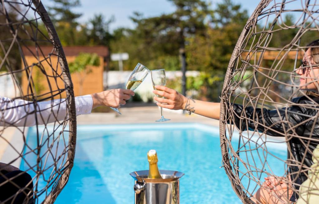 Due persone che tengono bicchieri di vino vicino a una piscina di VSG Resort a Klimno