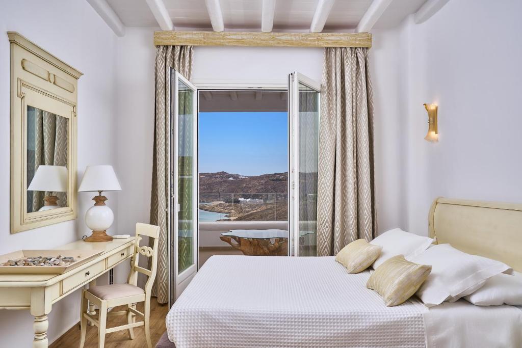a bedroom with a bed and a desk and a window at Arte & Mare Elia Luxury Suites and Villas in Elia Beach