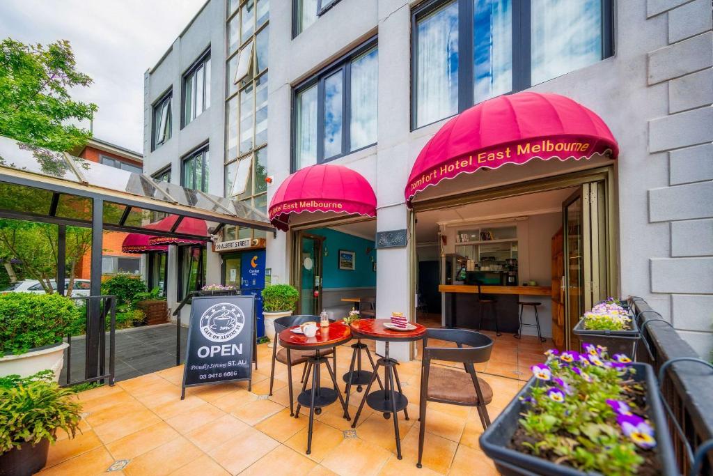 eine Terrasse mit Tischen und Stühlen vor einem Gebäude in der Unterkunft Comfort Hotel East Melbourne in Melbourne