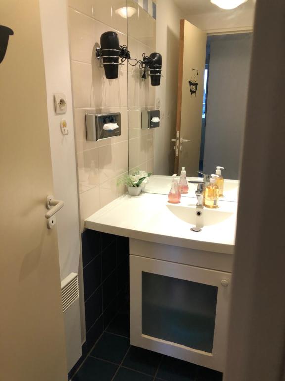 La salle de bains est pourvue d'un lavabo blanc et d'un miroir. dans l'établissement Ryan Homes - in ApartHotel - La Défense, à Courbevoie
