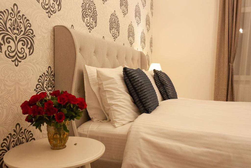 a bedroom with a white bed and a vase with red flowers at Cozy Family Apartments in Braşov