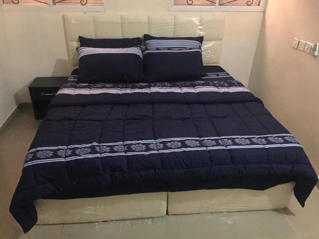 a bed in a room with a black and white comforter at Elstine’s in Lagos