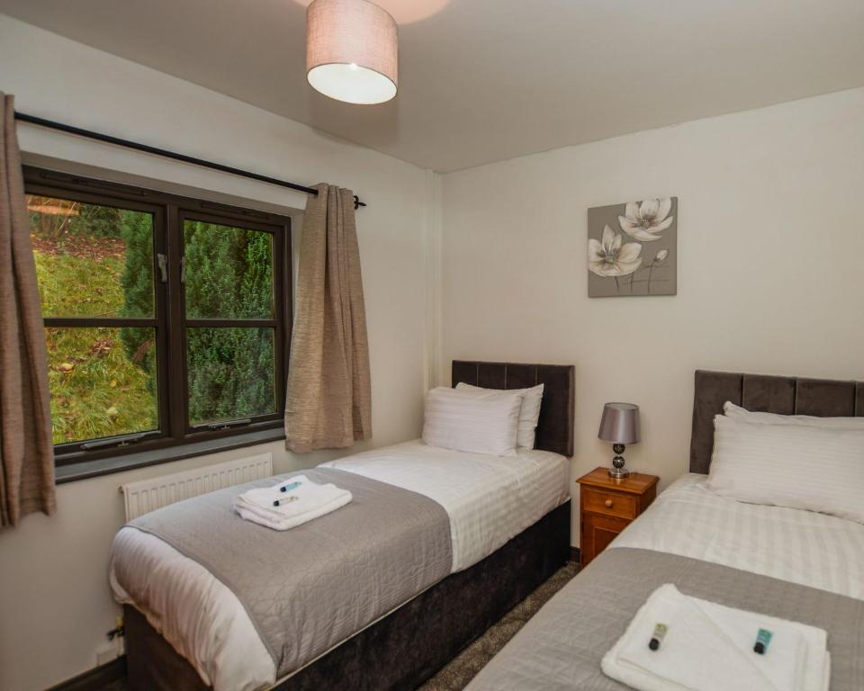 twee bedden in een kamer met een raam bij Conwy Valley Hotel Cottages in Conwy