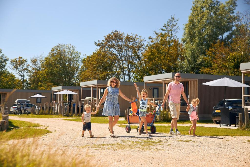 een familie die over een onverharde weg loopt met een kruiwagen bij RCN Vakantiepark Toppershoedje in Ouddorp