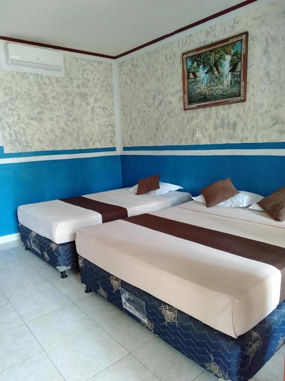 three beds in a room with blue walls at Cozy Alfia Inn in Gili Trawangan