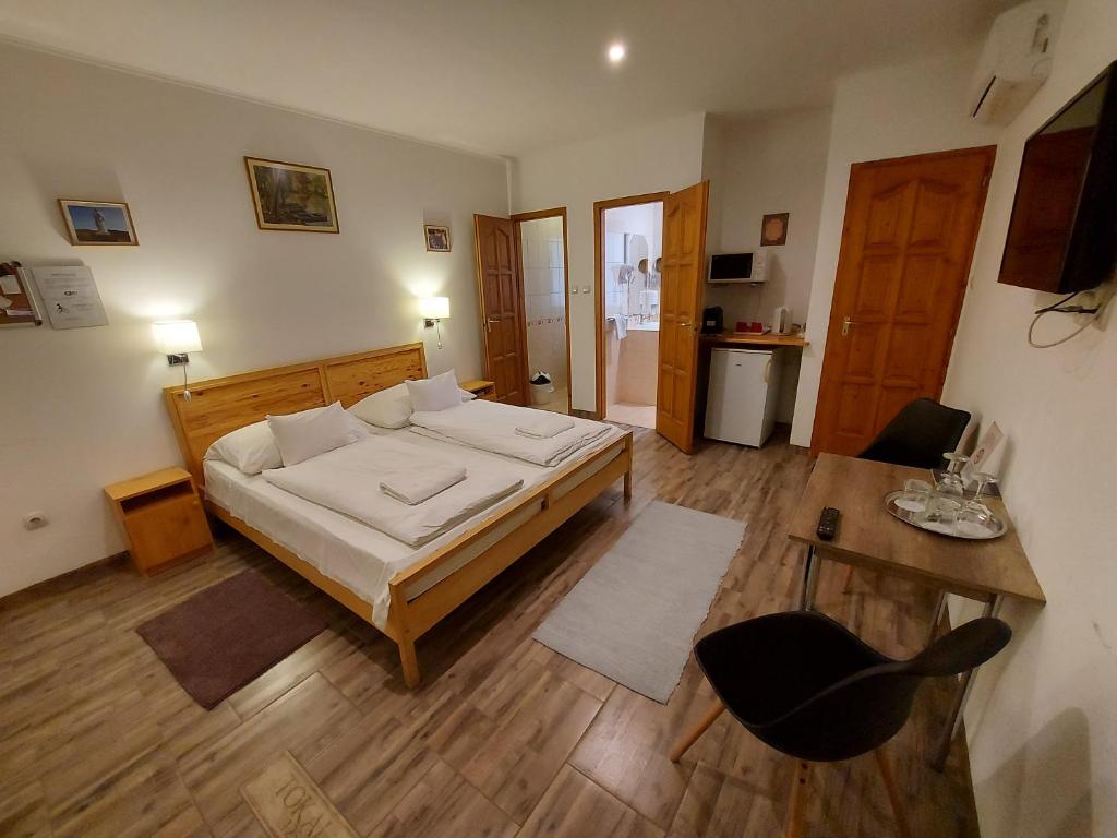 een slaapkamer met een bed, een tafel en een stoel bij Böne Vendégház és Borozó in Tokaj