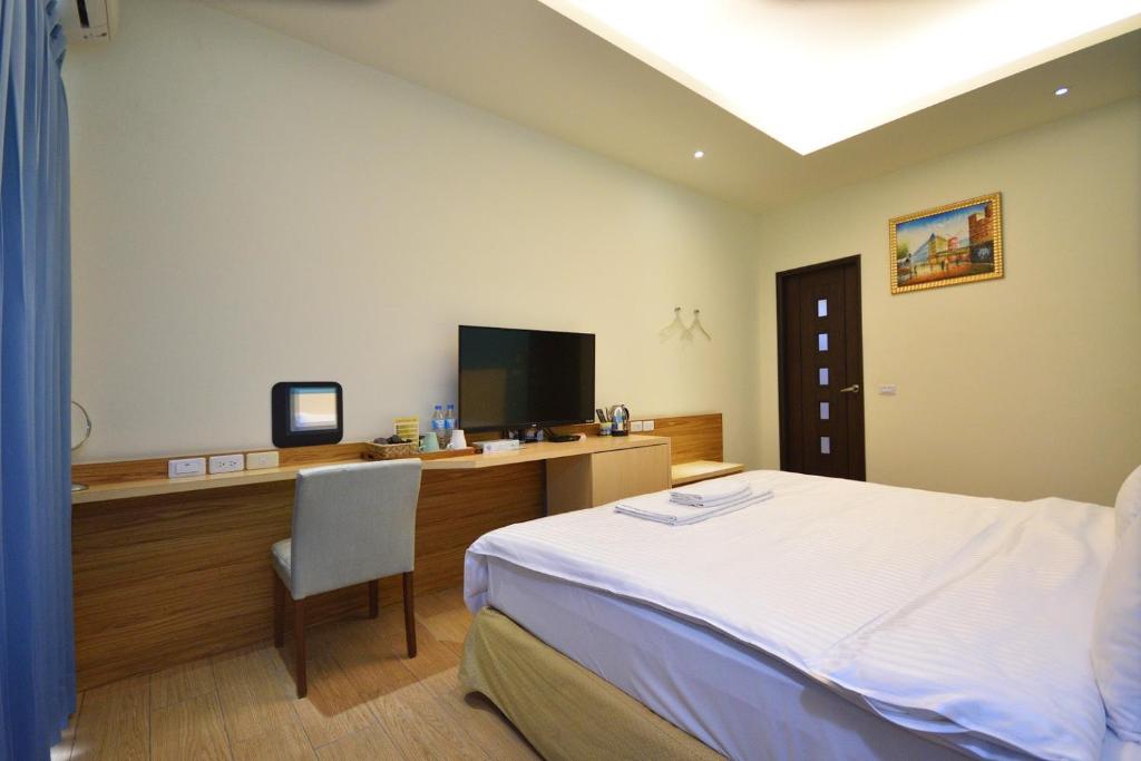 a bedroom with a bed and a desk with a television at Taitung Venice B&B in Taitung City