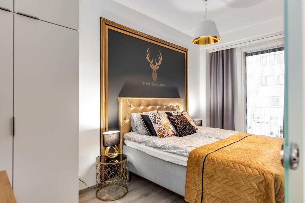 a bedroom with a king sized bed with a gold headboard at Trendy Homes Oulu Marski Apartments in Oulu