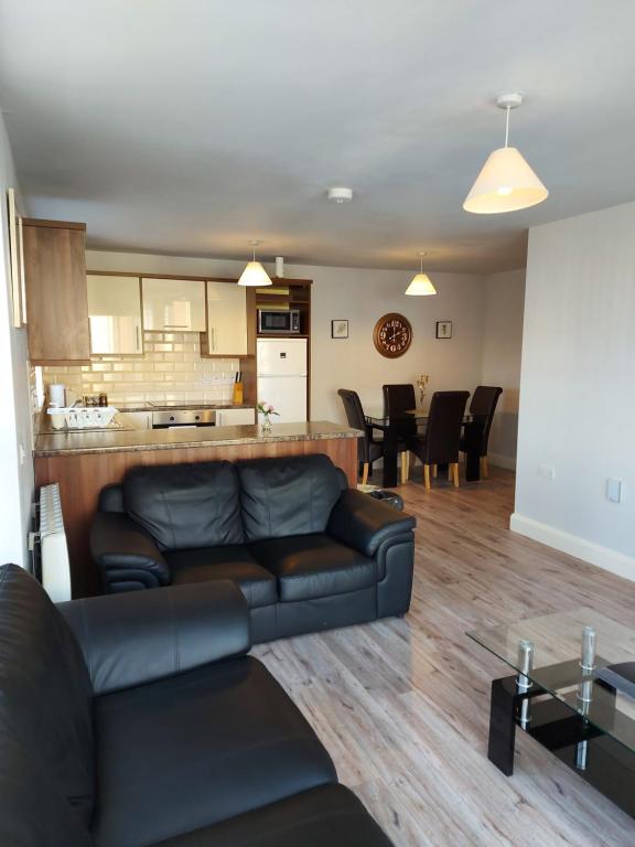 a living room with a couch and a kitchen at Wild Atlantic Apartments Killarney in Killarney