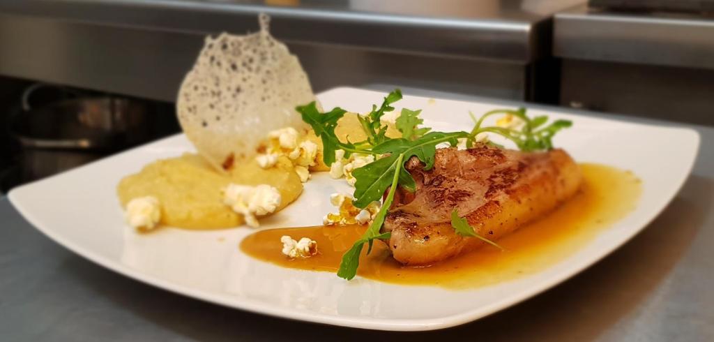 a white plate with food on a table at Hotel La Peyrade in Cajarc
