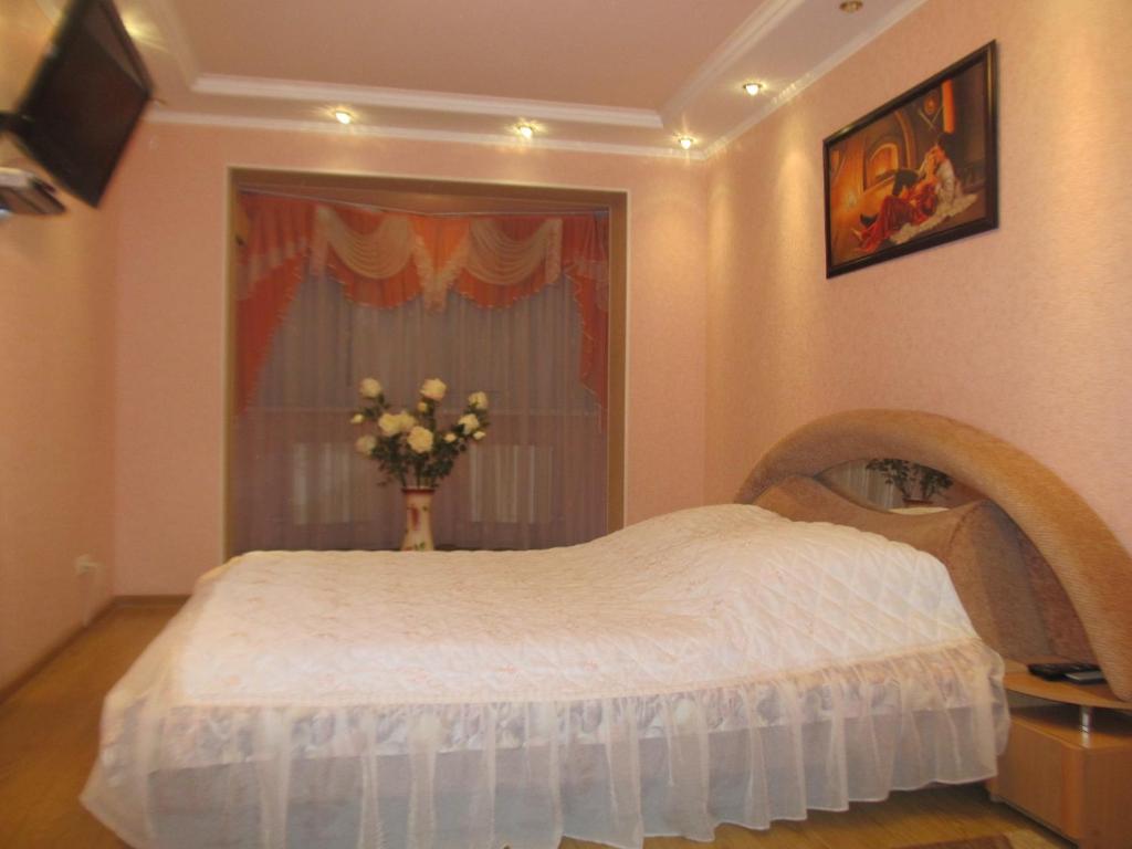 a bedroom with a white bed with a vase of flowers at Tiraspol Apartments in Tiraspol