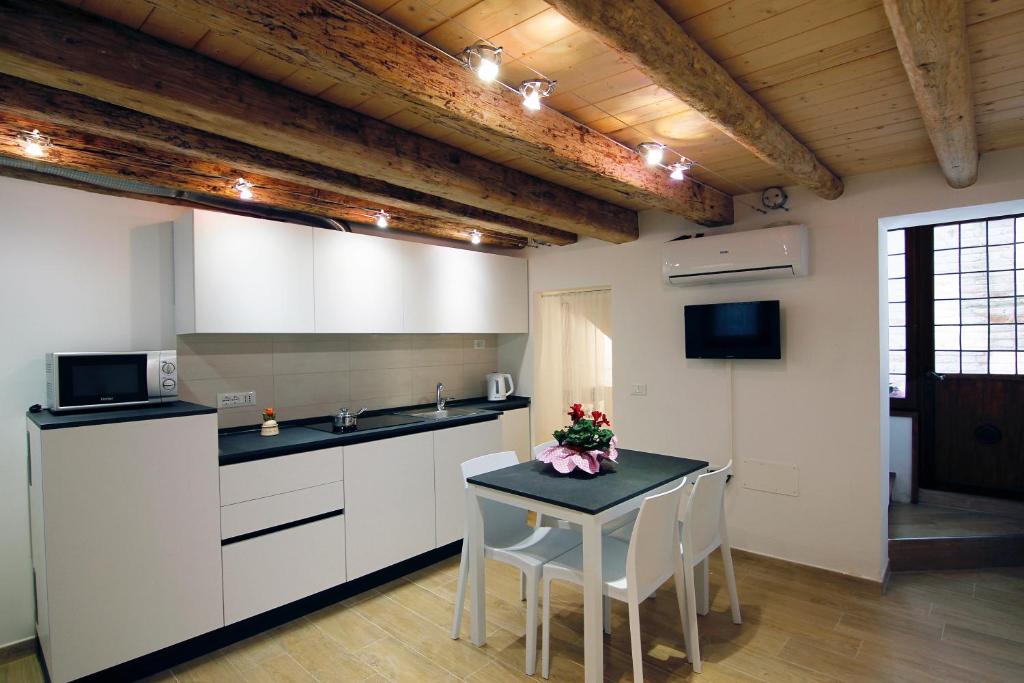 een keuken met witte kasten en een tafel met stoelen bij Tre Raggi Apartment in Venetië