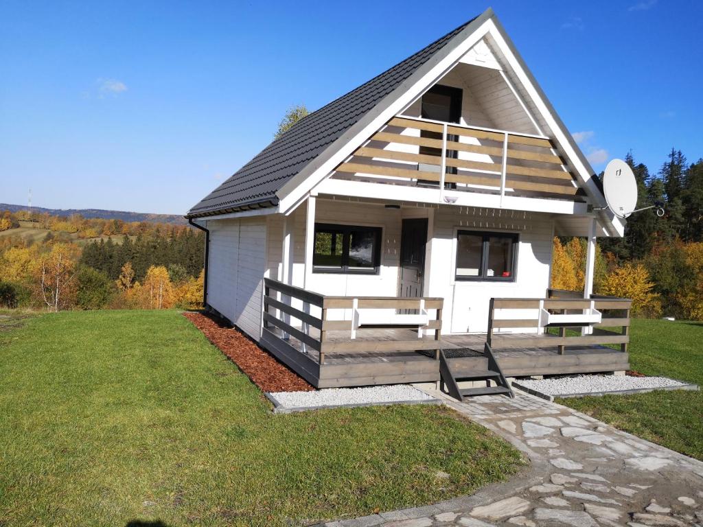 una pequeña casa blanca con un banco delante en Bajkowe Domki en Duszniki Zdrój