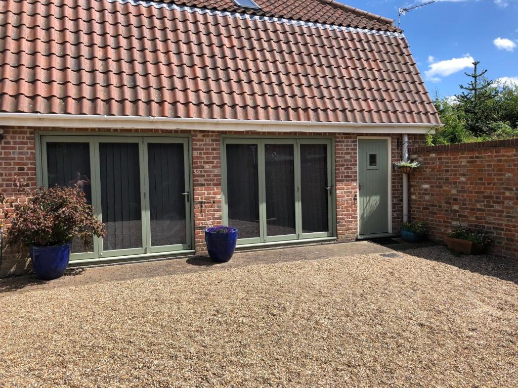 a house with windows and a brick wall at The Garden Loft in Freethorpe