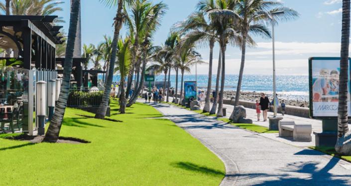 una acera junto a una playa con palmeras y el océano en Villa Meloneras - Exclusive Chill Out en San Bartolomé