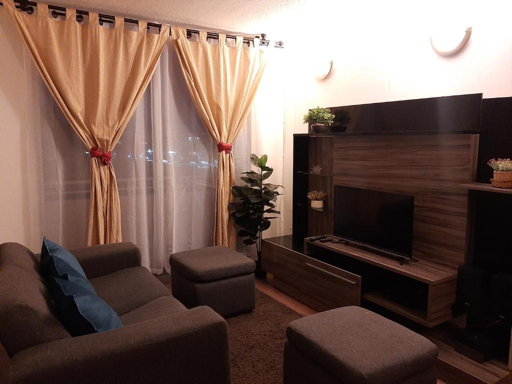 sala de estar con sofá y TV en Apartamento Alturas del Elqui 417, en La Serena