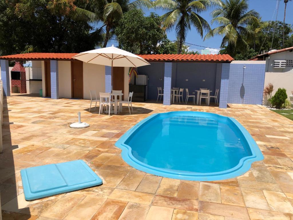 una piscina en un patio con sombrilla en Suite 100m da praia de Porto de Galinhas, en Porto de Galinhas