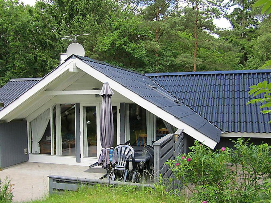 une maison avec un parasol et des chaises sur une terrasse dans l'établissement Three-Bedroom Holiday home in Hals 33, à Øster Melholt