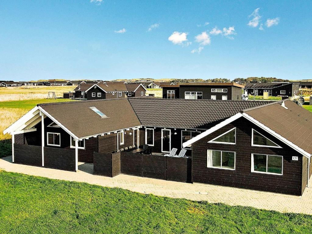 una casa marrón con techo en un campo en 20 person holiday home in L kken, en Løkken