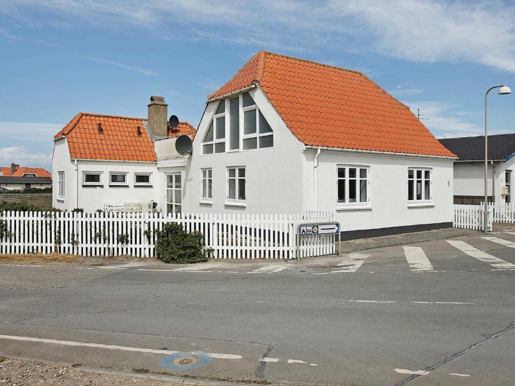uma casa branca com um telhado laranja atrás de uma cerca branca em 4 person holiday home in Lemvig em Trans