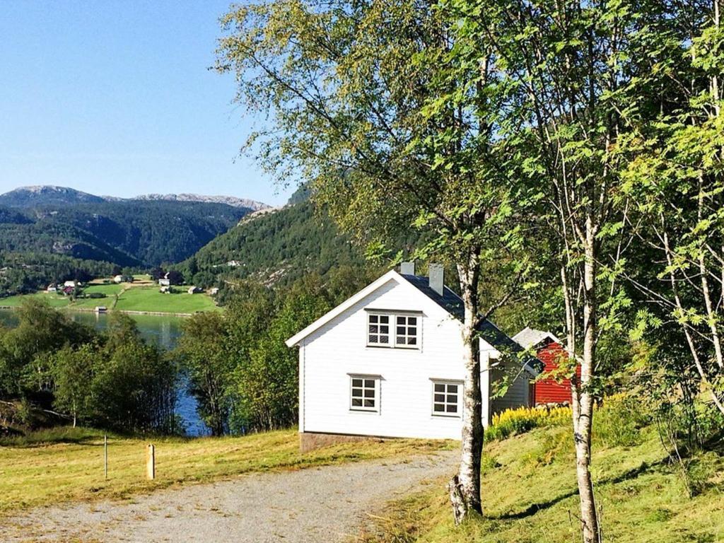 a white house on a hill next to a lake at Holiday home Masfjordnes in Masfjorden