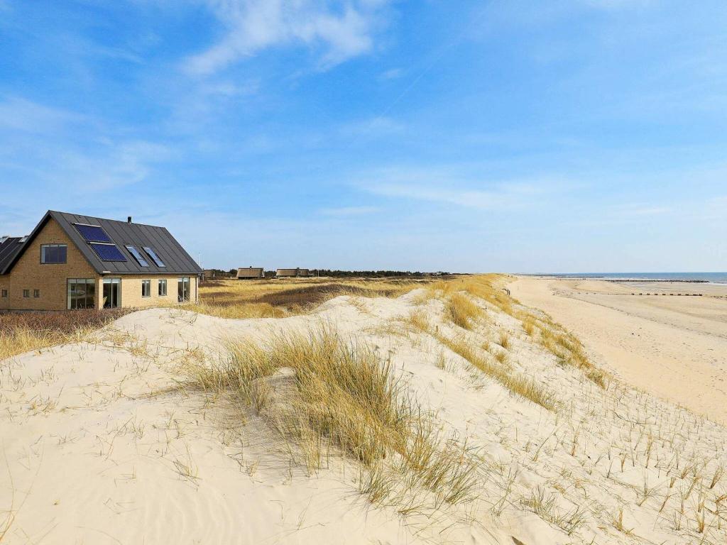 ブラーバンドにある6 person holiday home in Bl vandの砂浜の上に腰掛けた家