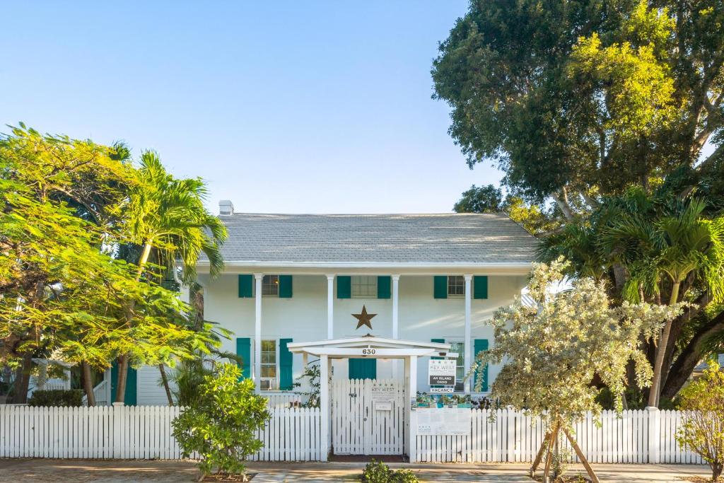 ein weißes Haus mit einem weißen Zaun und einem Regenschirm in der Unterkunft An Island Oasis in Key West