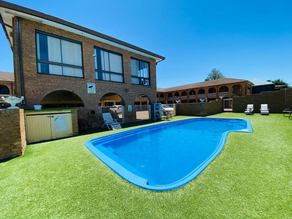 a large blue swimming pool in the yard of a house at Cumberland Motor Inn in Cessnock