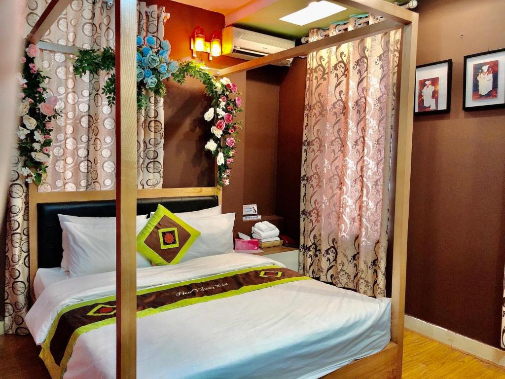 a bedroom with a four poster bed with flowers at Phuong Dong hotel in Hanoi
