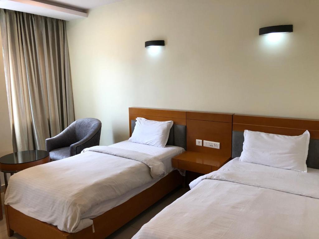 ein Hotelzimmer mit 2 Betten und einem Stuhl in der Unterkunft Leela pavilion in Rājahmundry