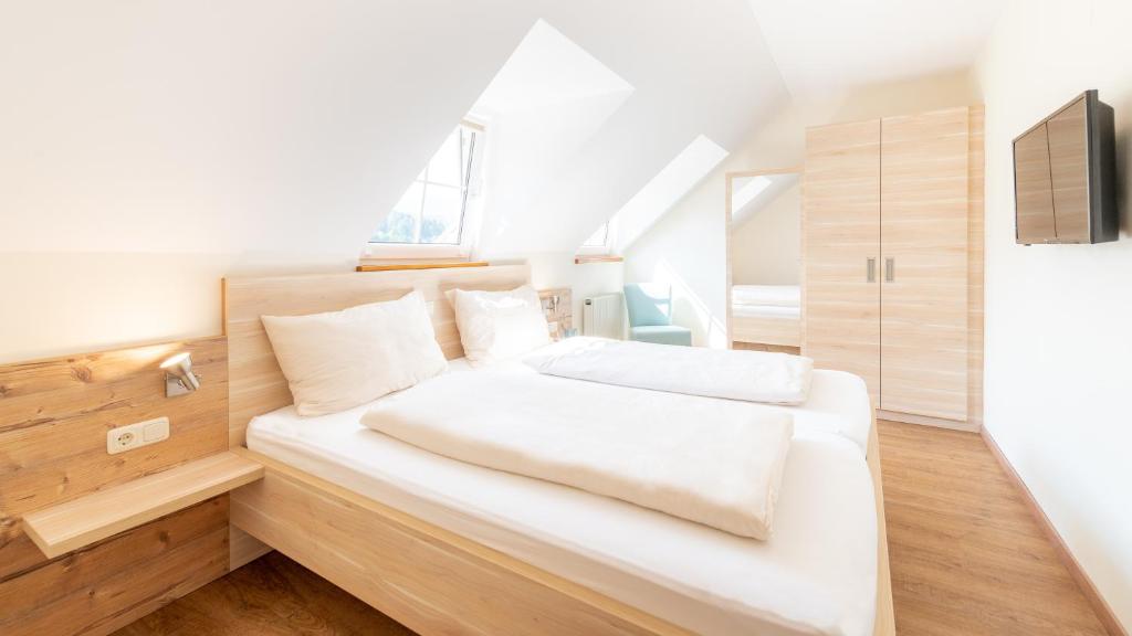 a bedroom with a white bed and a tv at Pension Pirkdorfer See in Sankt Michael ob Bleiburg