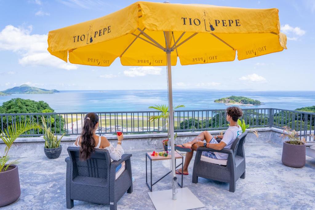 two people sitting in chairs under a yellow umbrella at Kolibri Holiday Apartments in Victoria