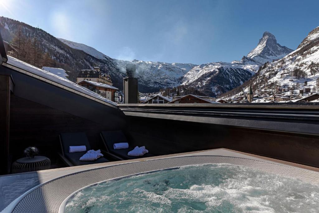 a hot tub with a view of a snowy mountain at Hotel ZERMAMA Zermatt in Zermatt