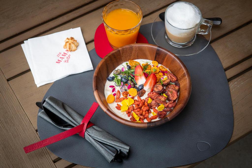 a bowl of food on a table with a glass of orange juice at Hotel ZERMAMA Zermatt in Zermatt