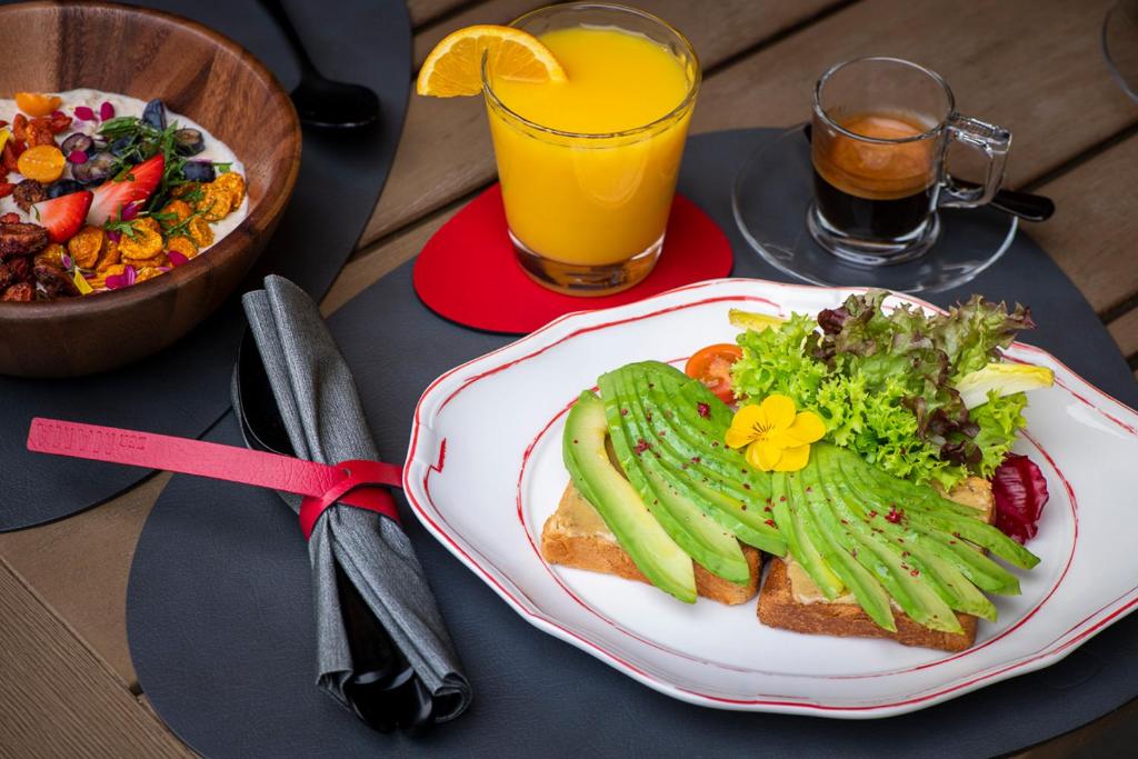 a table with a plate of food and a salad and juice at Hotel ZERMAMA Zermatt in Zermatt