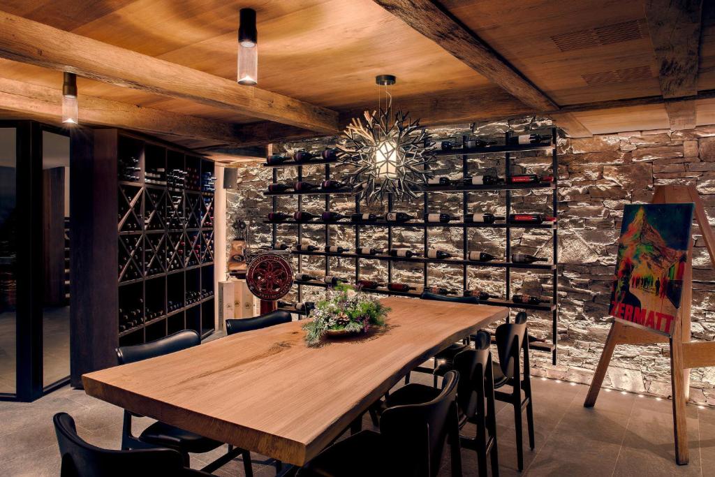 a dining room with a table and a wall of wine bottles at Hotel ZERMAMA Zermatt in Zermatt