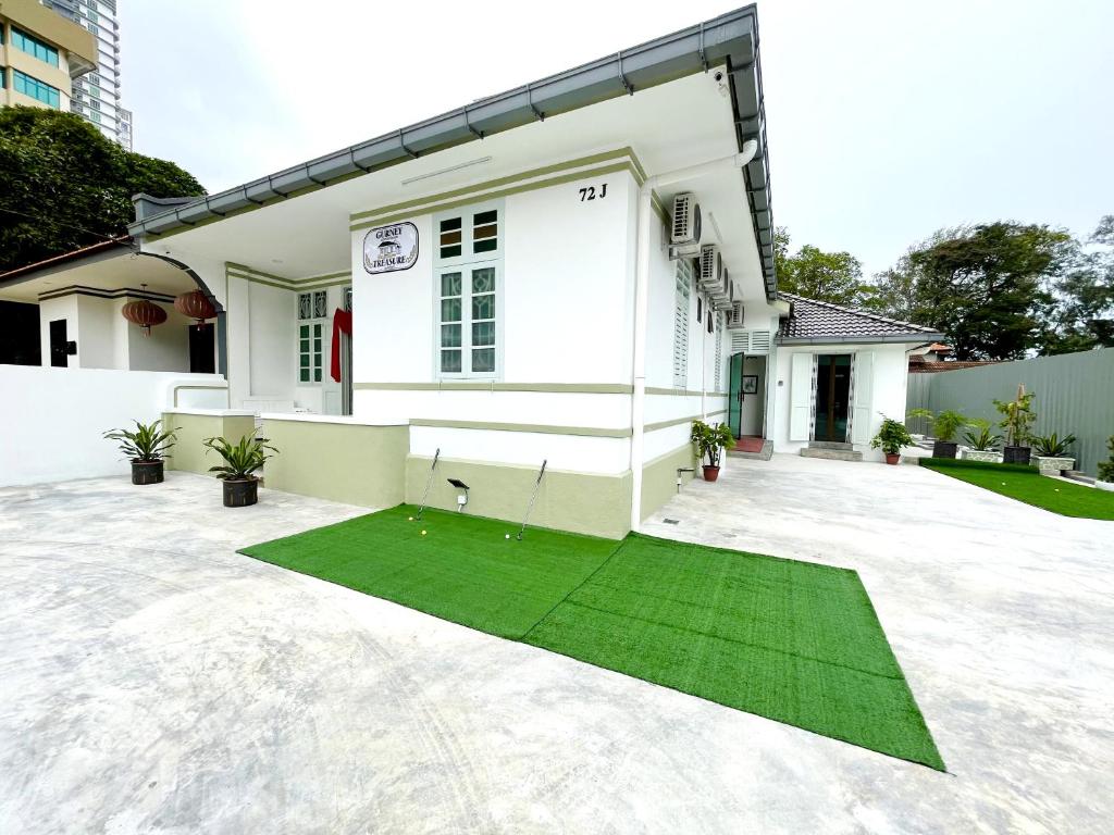 a white house with a green lawn in front of it at Gurney Treasure - The Vintage Villa by Little Cabin in George Town