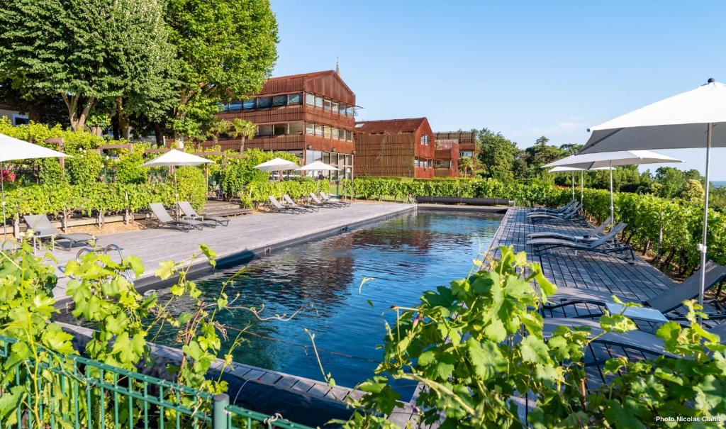 une piscine dans un hôtel avec des chaises et des parasols dans l'établissement Hôtel Le Saint-James, à Bouliac