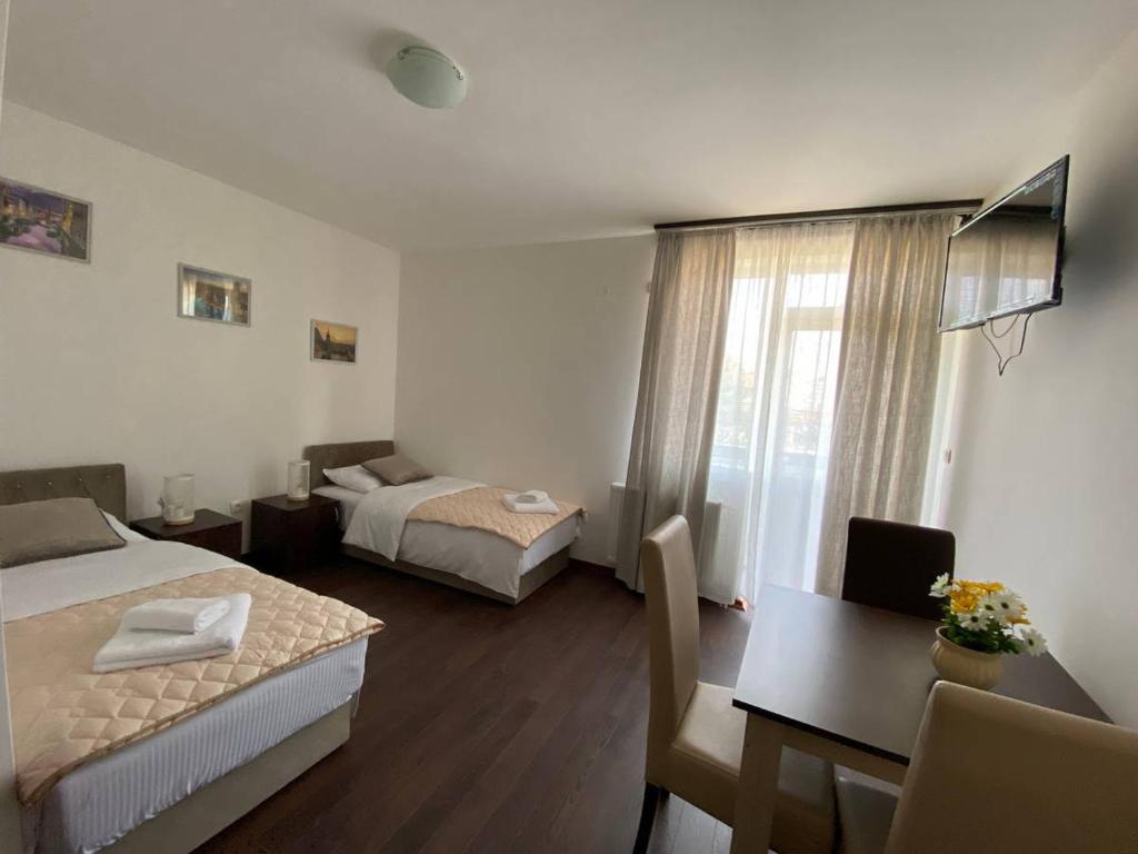 ein Hotelzimmer mit 2 Betten, einem Tisch und einem Schreibtisch in der Unterkunft Podrinjski san in Loznica