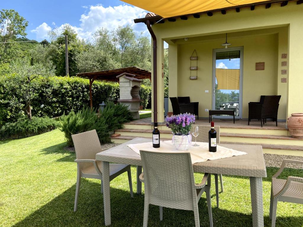 uma mesa e cadeiras com garrafas de vinho num pátio em Casa di Campagna Pianelli em Pergine Valdarno