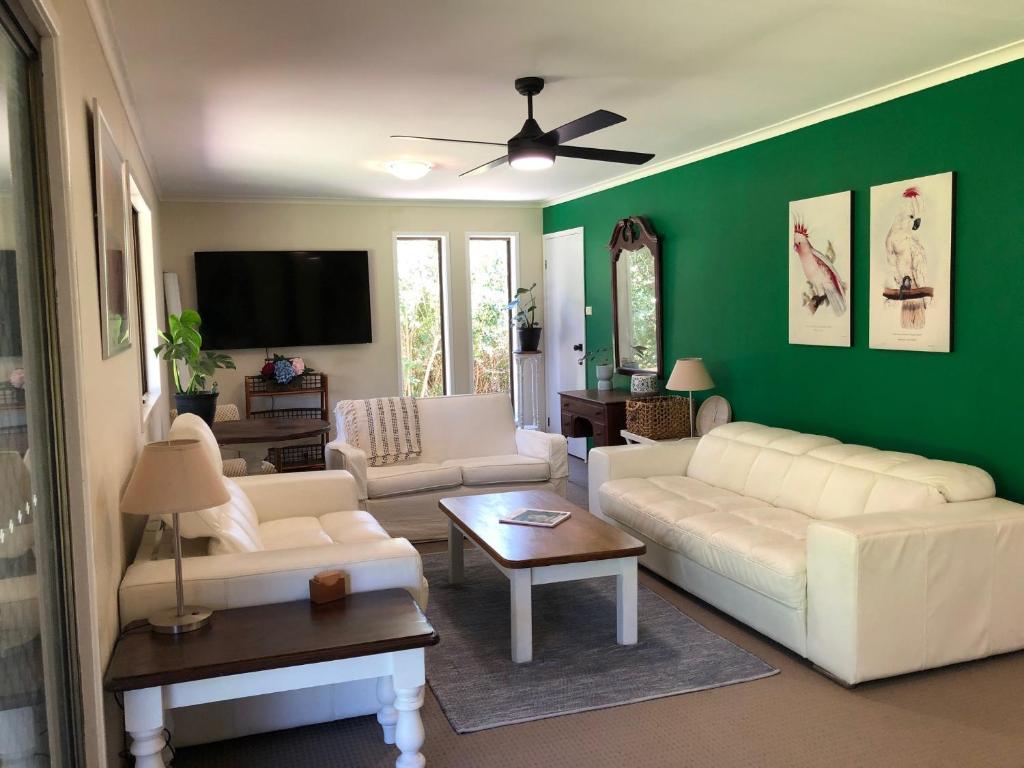 a living room with white furniture and a green wall at Bowral Bungalow in Bowral