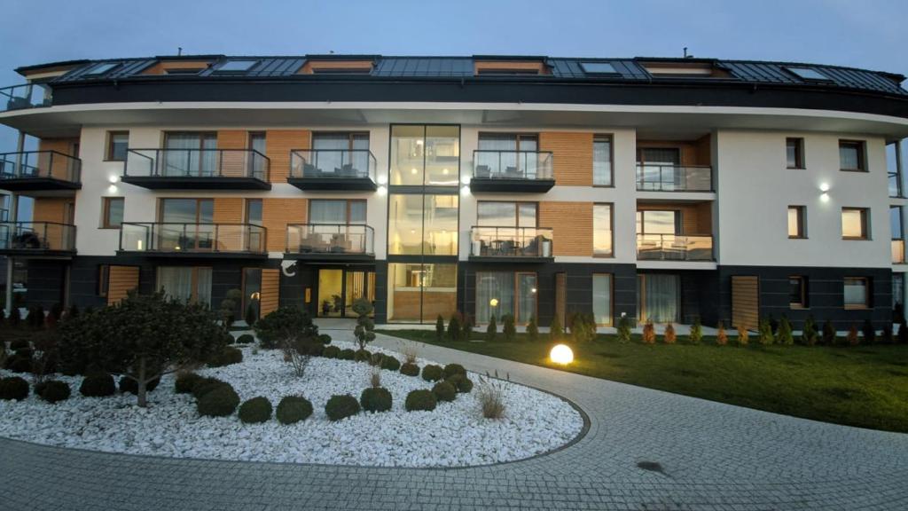 un grand bâtiment avec un jardin en face dans l'établissement APARTAMENT BLUE , Marynarska 8 , Sarbinowo, à Sarbinowo
