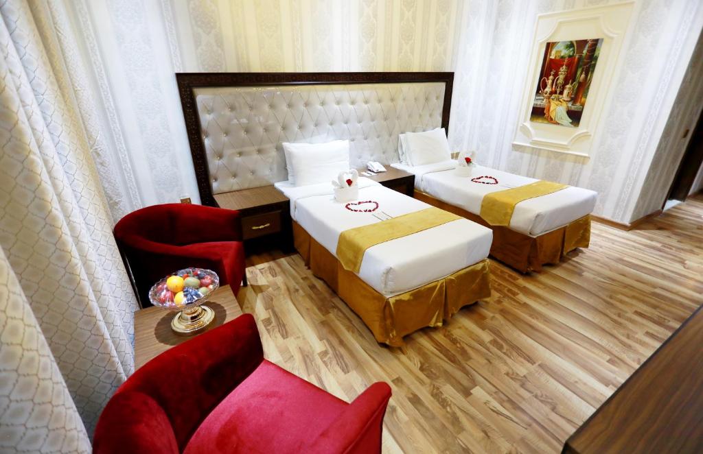 a hotel room with two beds and a chair at Ras Al Khaimah Hotel in Ras al Khaimah