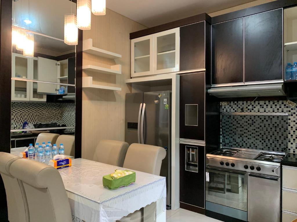 a kitchen with a table and a refrigerator at Platinum Setramurni Guest House Bandung 3BR in Bandung