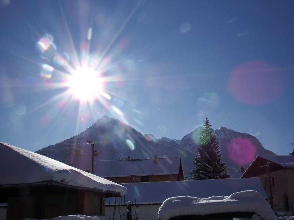 a sun shining over a mountain with snow on the ground at Le Bacchu Ber in Briançon