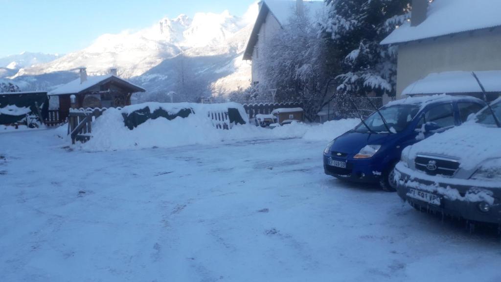 two cars parked in a driveway covered in snow at Le Bacchu Ber in Briançon